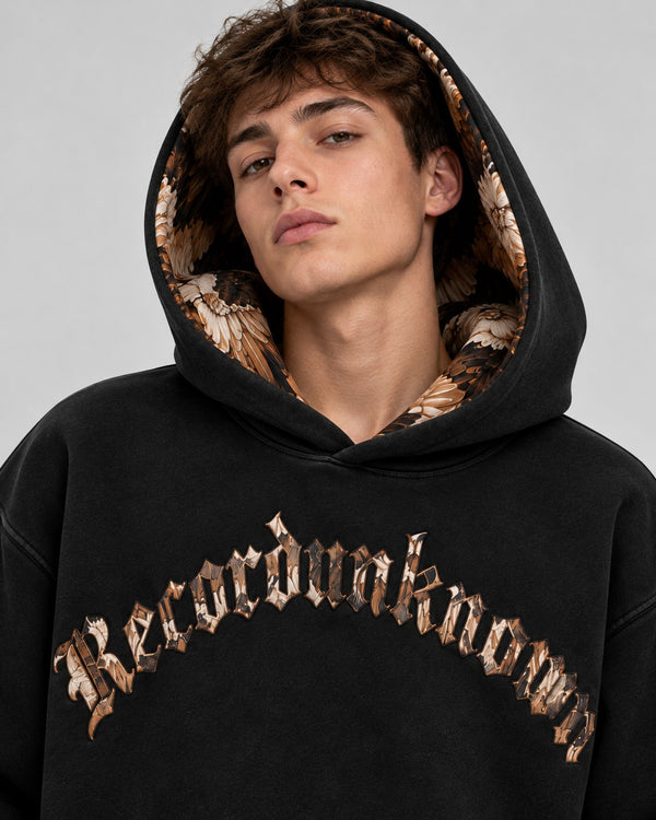 Model wearing the Recordunknown Eagle Hoodie Black, hood up showing the eagle feather lining