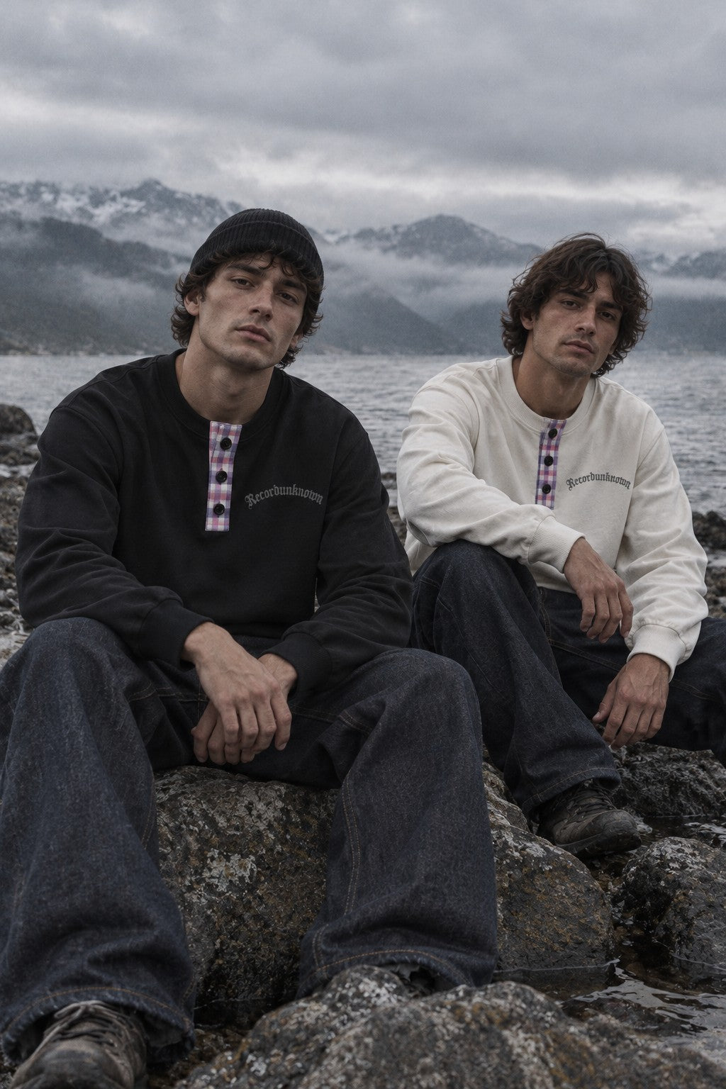 Two models by a lake wearing the Recordunknown black and bone flannel henleys