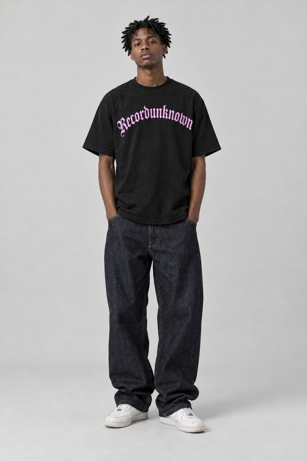 Model wearing the Recordunknown black logo tee, full-length studio shot